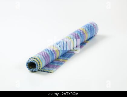 Colorful striped ribbed woven cotton place mat - rolled up Stock Photo