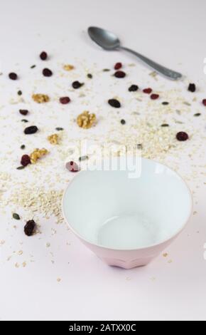 Empty cereal bowl with healthy cereal or granola spilled on the table and a spoon in the background Stock Photo