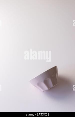 Empty pink cereal bowl flipped to the side, vertical, pastel colors, space to add text for breakfast Stock Photo