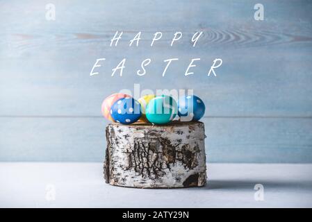 Colorful decorated bright Easter eggs on a birch stump. Festive spring card with text Stock Photo