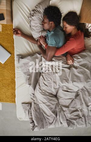 High angle view of multiethnic young couple resting in bed and enjoying the dream together in the bedroom Stock Photo