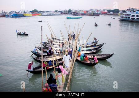 People getting off wooden boat at boat terminal in burigonga river for crossing river at sadarghat dhaka bangladesh Stock Photo