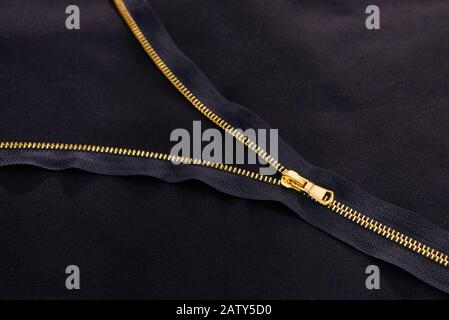 Open golden zipper on black fabric Stock Photo