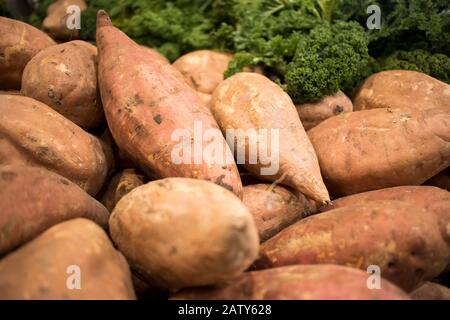 Sweet potatoes in a wooden box for sale on a counter at Borough Market Stock Photo