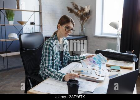 Female interior designer working in office with color palette. Architect select colors for building using color swatches, searching new ideas for proj Stock Photo