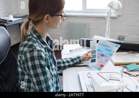 Female interior designer working in office with color palette. Architect select colors for building using color swatches, searching new ideas for proj Stock Photo