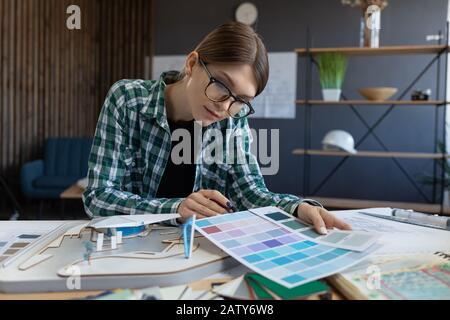 Female interior designer working in office with color palette. Architect select colors for building using color swatches, searching new ideas for proj Stock Photo