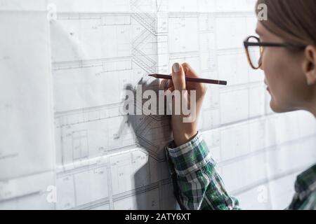 Close-up portrait of beautiful woman concentrated on work. Architect working in office with blueprints. Engineer sketching a construction project. Arc Stock Photo
