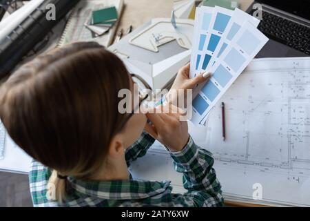 Female interior designer working in office with color palette. Architect select colors for building using color swatches, searching new ideas for proj Stock Photo