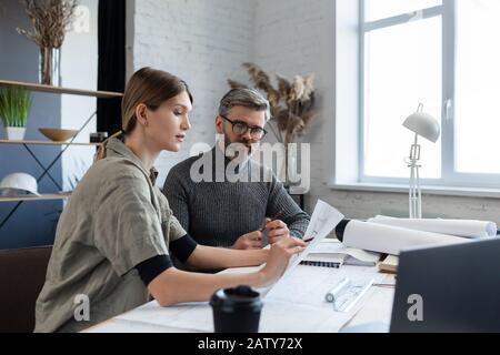 Engineer team working in office with blueprints and architect equipment, sketching, negotiating and planning construction project. Partners discussing Stock Photo