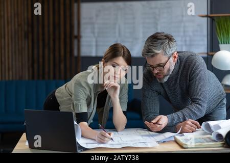 Engineer team working in office with blueprints and architect equipment, sketching, negotiating and planning construction project. Partners discussing Stock Photo