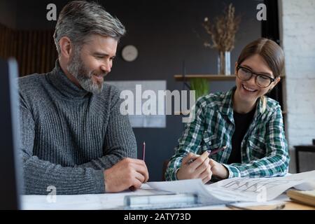 Interior designers team working in office with blueprints and architect equipment, sketching, negotiating and planning construction project. Partners Stock Photo