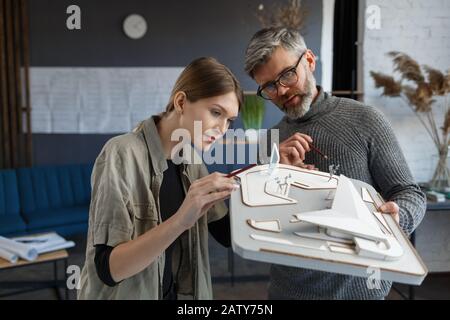 3d architects team working in office with building 3d model. Architects inspect building layout, planning construction project, searching new ideas. P Stock Photo