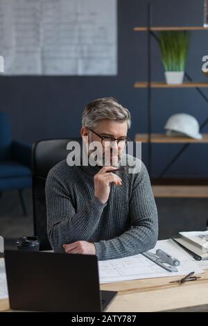 Interior designer working in office with blueprints.Engineer inspect architectural plan, sketching a construction project.Portrait of handsome bearded Stock Photo