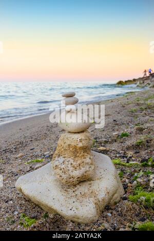 Relax time. Sunset at black sea. Rocky coast near Varna in Bulgarian. Stack of pebbles. Stock Photo