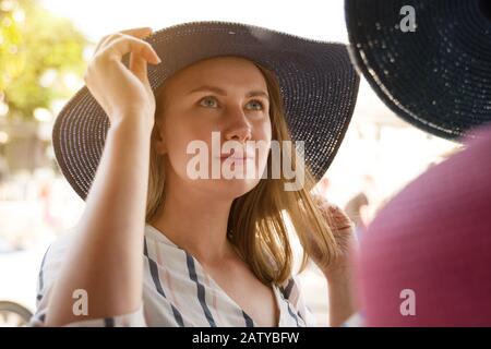 Pretty woman choosing hat in shop on vacation. Stock Photo