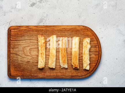 Pancakes with cottage cheese on an old kitchen cutting board on a gray concrete background, flat lay, image with copy space. Stock Photo
