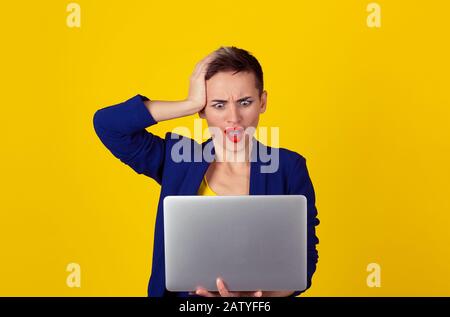 I got hacked.  Shocked business woman with laptop computer looking at screen isolated yellow background wall blue suit Human face expression emotion f Stock Photo