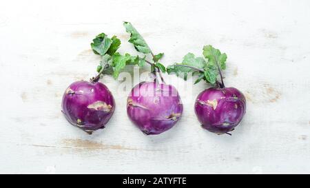 Kohlrabi cabbage with green leaves on wooden background. Top view. Free space for your text. Stock Photo