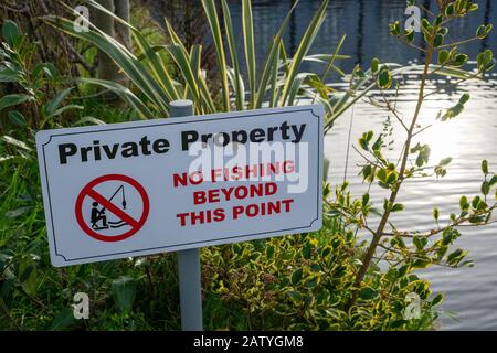 A sign on a river bank reading private property no fishing beyond this point Stock Photo