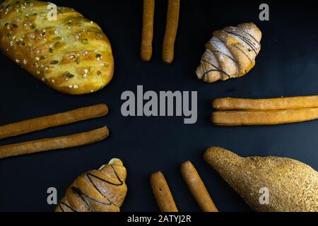 Different types of fresh bread with grain on a black rustic background. the bread stands around Stock Photo