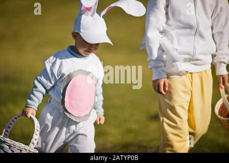 Two brothers in Easter costumes on an Easter egg hunt Stock Photo