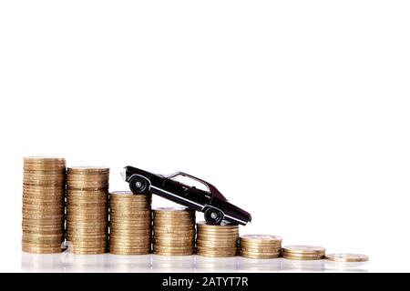 A black model of a car with coins in the form of a histogram on a white background. Concept of lending, savings, insurance. Stock Photo