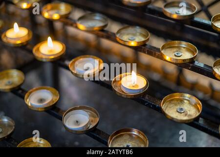 candles lit on a stand in a church in remembrance Stock Photo