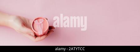 Round pink gift box in women's hands on a pink background. Festive concept for Valentine's day, Mother's day or birthday Stock Photo