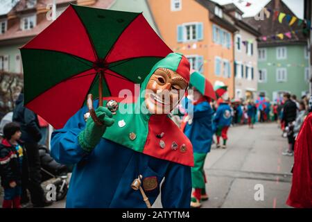 Oberwindemer Spitzbue - Fastnachts Fool with red-green hood and umbrella. During the carnival parade in Staufen, southern Germany. Stock Photo