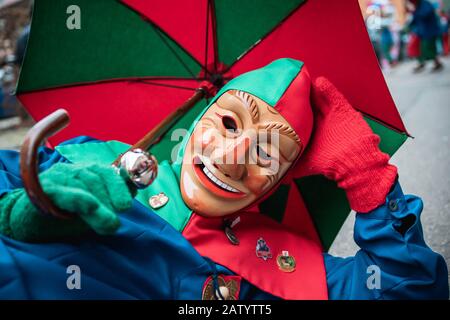 Oberwindemer Spitzbue - Fastnachts Fool in red-green robe and umbrella lies comfortably on the floor during the carnival parade in Staufen, southern G Stock Photo