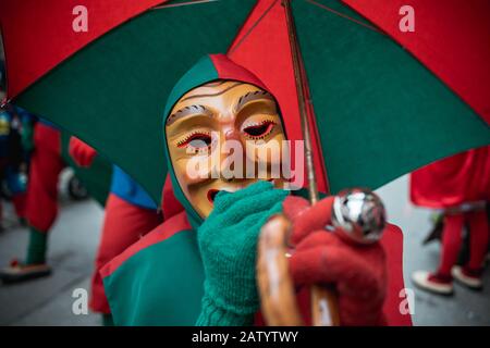 Oberwindemer Spitzbue - Carnival fool in red-green robe and umbrella during Carnival parade in Staufen, southern Germany. Stock Photo