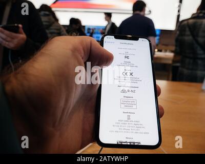 Paris, France - Nov 3, 2017: POV of male hand customer admiring inside Apple Store the latest professional iPhone smartphone manufactured by Apple Computers and certifications of the headset Stock Photo