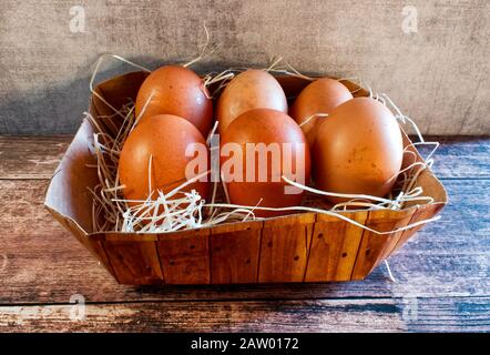 Fresh eggs in a basket on wooden table Stock Photo