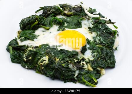 Plate of fried egg, mozzarella, and spinach on wooden table Stock Photo