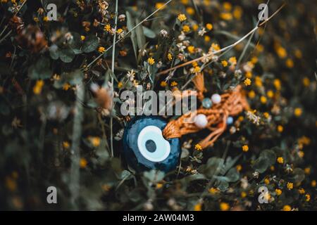 A beautiful evil eye bead among the flowers on the ground. Culture Concept. Stock Photo