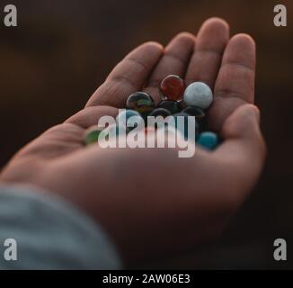 Outside person holding beautiful marble balls in his hands at sunset. Childhood Concept. Stock Photo