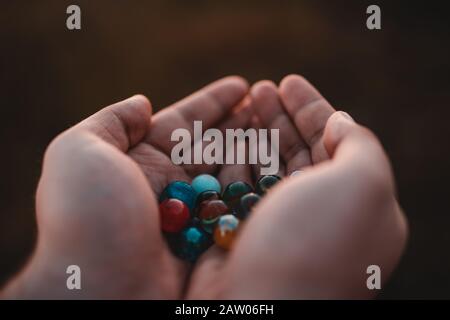 Outside person holding beautiful marble balls in his hands at sunset. Childhood Concept. Stock Photo