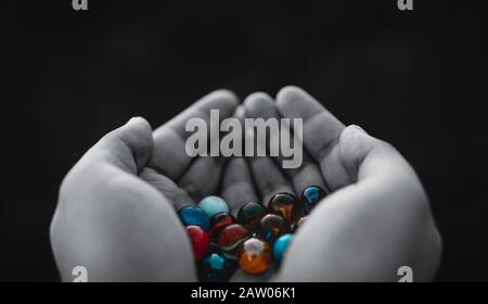 Outside person holding beautiful marble balls in his hands at sunset. Childhood Concept. Stock Photo