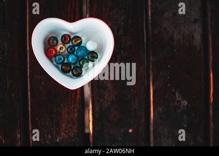 Heart shaped marble bowl on the table, marble balls inside. Background Concept. Stock Photo