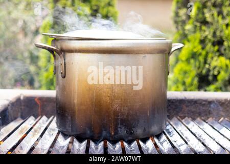 Preparation of soup in a pot, in nature. Cooking soup through the wood fire Stock Photo