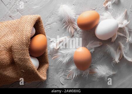 Zero concept, village eggs in sackcloth with chicken fluff, flat lay food Stock Photo