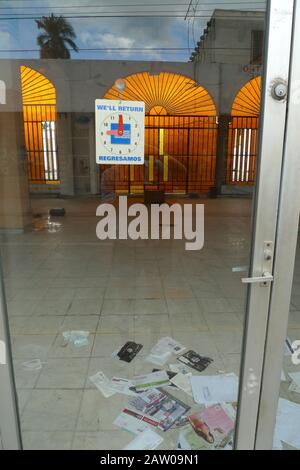 No return - a 'we will return' sign shows an empty building with old mail on the floor. The sign lends the abandoned building has an ironic quality. Stock Photo