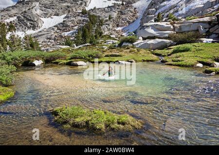 Asian woman shocked by dip in icy cold mountain stream Stock Photo