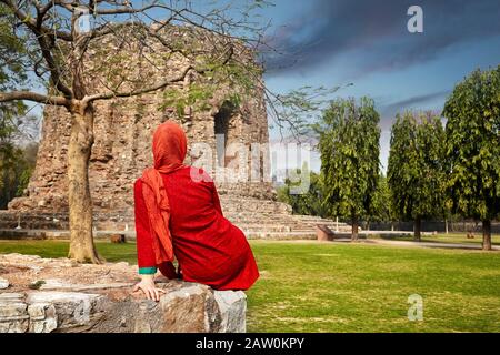 Indian woman in red dress near Qutub Minar tower in Delhi, India Stock Photo