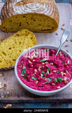 Homemade roasted beetroot hummus and turmeric sourdough bread on a slate background