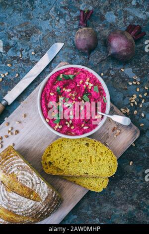 Homemade roasted beetroot hummus and turmeric sourdough bread on a slate background Stock Photo