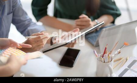 Close up view of application developer team using digital tablet while consulting on their UI project in simple co working space Stock Photo