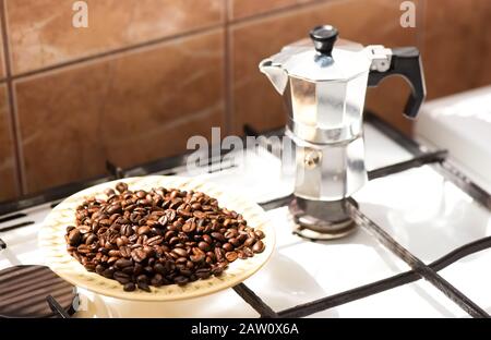 Coffee beans on a plate and moka coffe pot on a gas stove Stock Photo