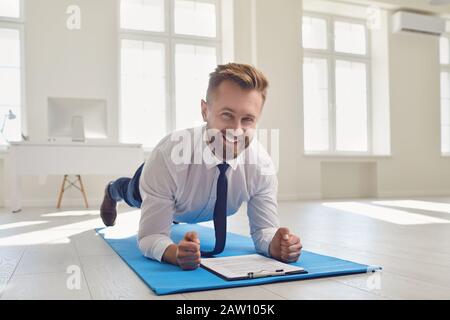 Businessman doing abs strap exercises while lying in the office. Stock Photo